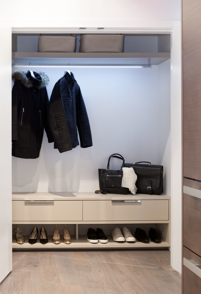 Small modern standard wardrobe in Vancouver with flat-panel cabinets, beige cabinets and light hardwood flooring.