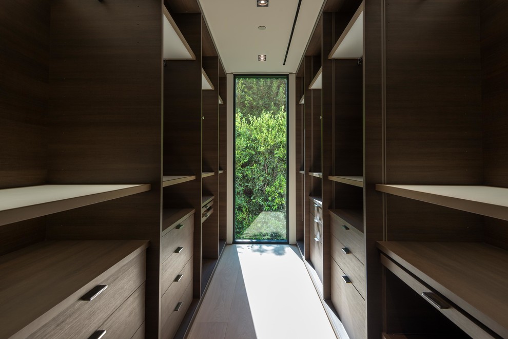 Immagine di una piccola cabina armadio unisex minimalista con nessun'anta, ante in legno bruno, parquet chiaro e pavimento beige