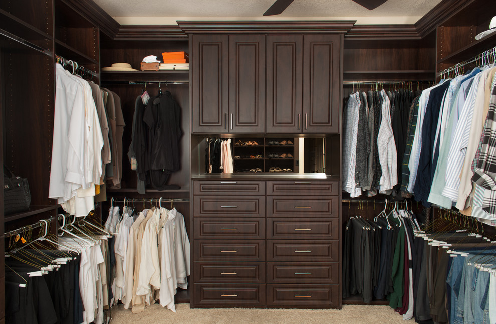 Ejemplo de armario vestidor de hombre clásico de tamaño medio con armarios con paneles con relieve, puertas de armario de madera en tonos medios y moqueta