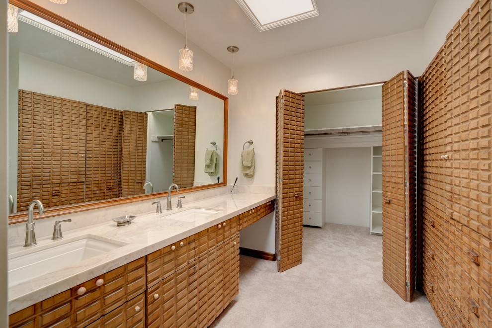 Aménagement d'un grand dressing room rétro en bois brun neutre avec moquette et un sol beige.