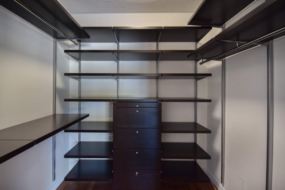 Ejemplo de armario vestidor unisex retro pequeño con armarios abiertos, puertas de armario de madera en tonos medios, suelo de madera oscura y suelo marrón