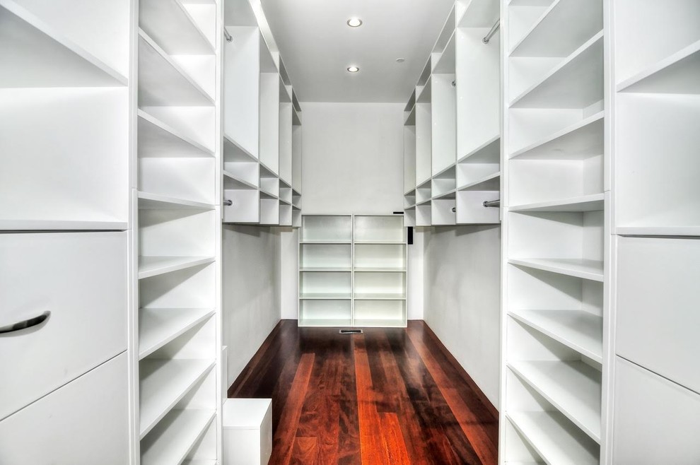 Example of a small trendy gender-neutral dark wood floor walk-in closet design in Orange County with open cabinets and white cabinets