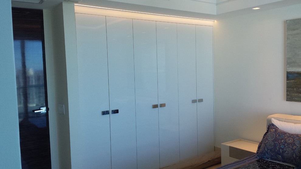 Aménagement d'un petit dressing room contemporain neutre avec un placard à porte plane et des portes de placard blanches.