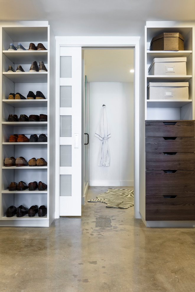 Foto de vestidor unisex minimalista de tamaño medio con armarios abiertos, puertas de armario blancas, suelo de cemento y suelo beige