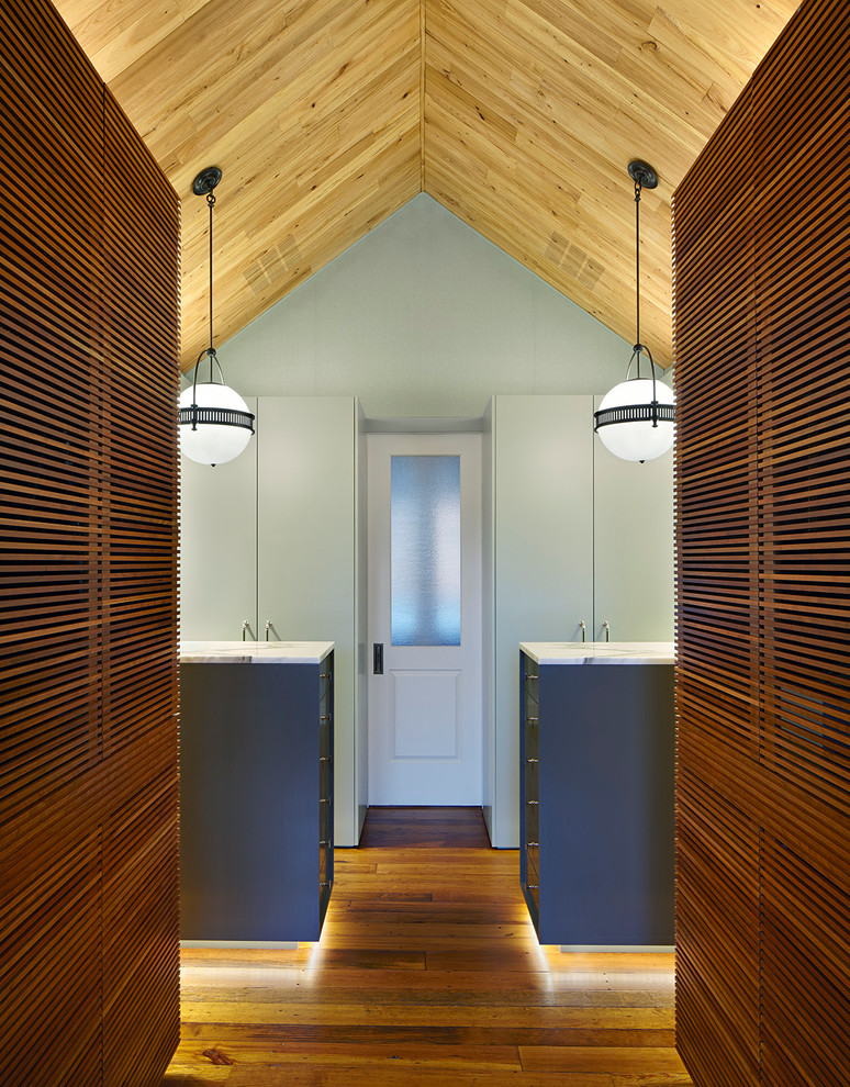 Esempio di un ampio spazio per vestirsi unisex design con ante lisce, ante bianche, pavimento in legno massello medio e pavimento marrone
