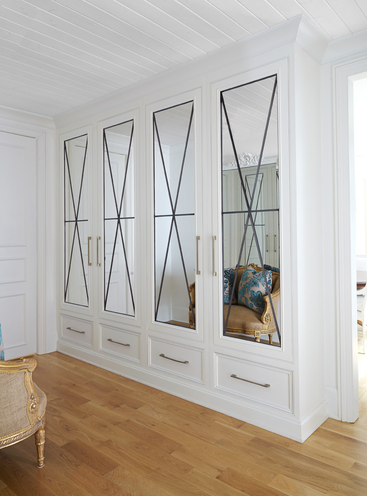 Cette photo montre un dressing room chic neutre avec un placard à porte affleurante, des portes de placard blanches et parquet clair.