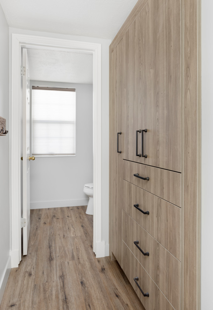 Imagen de armario unisex tradicional renovado pequeño con armarios con paneles lisos, puertas de armario de madera clara, suelo laminado y suelo marrón