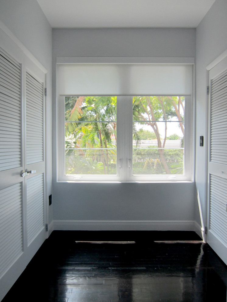This is an example of a large eclectic gender neutral dressing room in Miami with louvered cabinets, white cabinets and dark hardwood flooring.