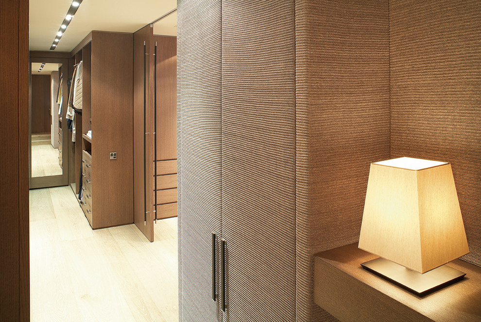 Foto de armario vestidor unisex contemporáneo grande con armarios con paneles lisos, puertas de armario de madera oscura y suelo de madera clara