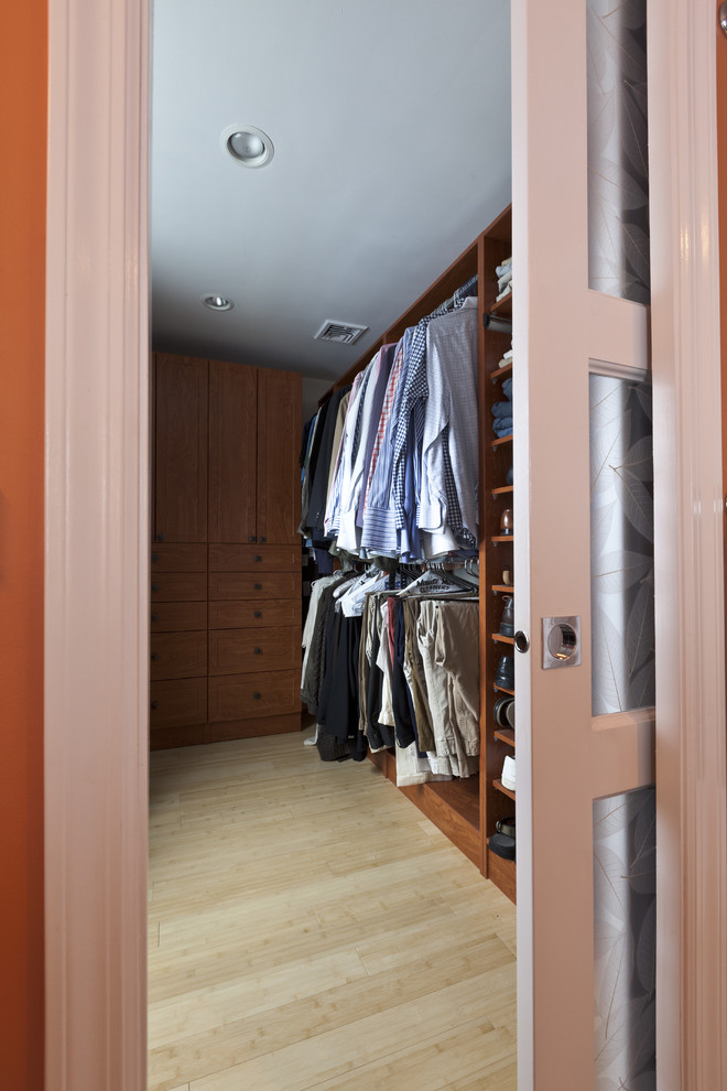 Imagen de armario vestidor unisex ecléctico de tamaño medio con armarios con paneles empotrados, puertas de armario de madera oscura y suelo de madera clara