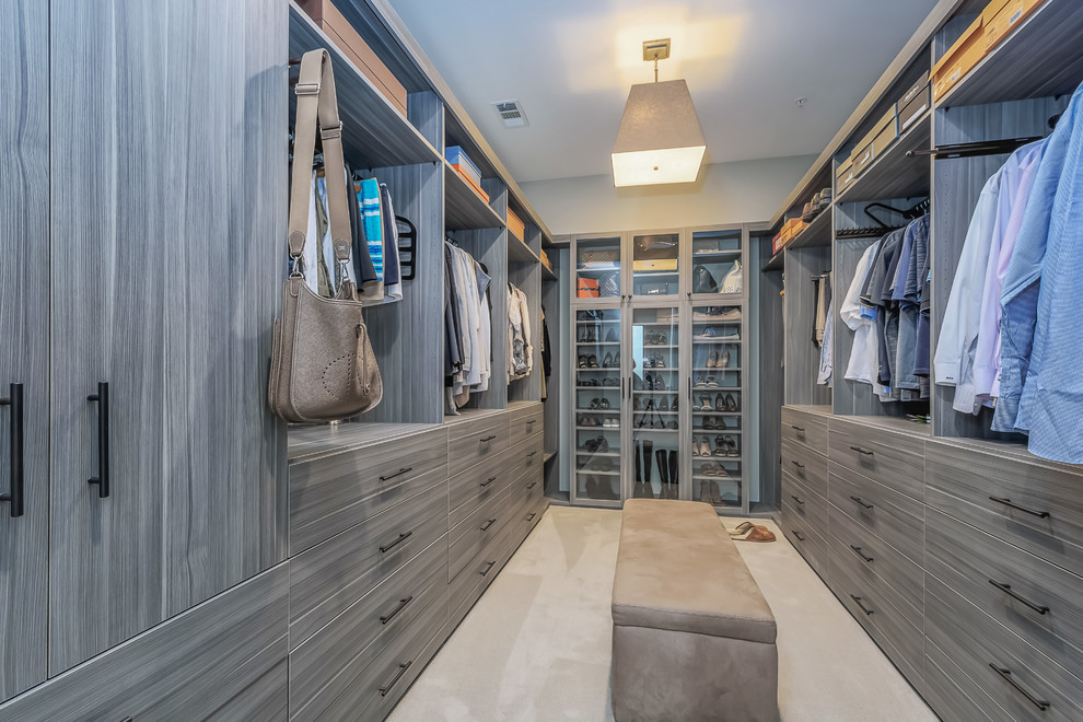 Large contemporary gender neutral dressing room in San Francisco with flat-panel cabinets, carpet, beige floors and grey cabinets.