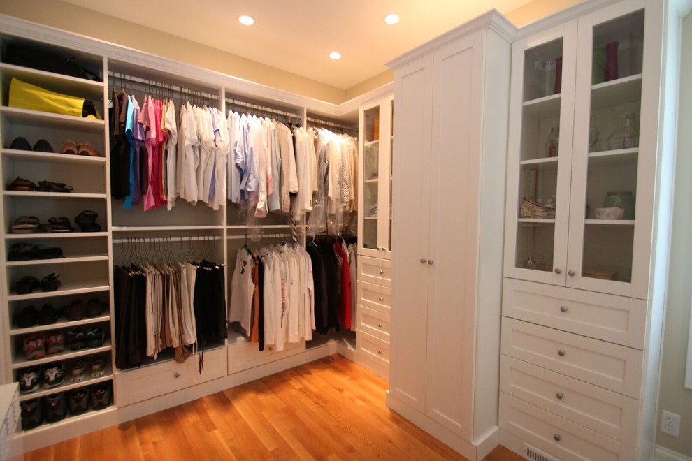 This is an example of a large traditional gender neutral walk-in wardrobe in New York with shaker cabinets, white cabinets, medium hardwood flooring and brown floors.