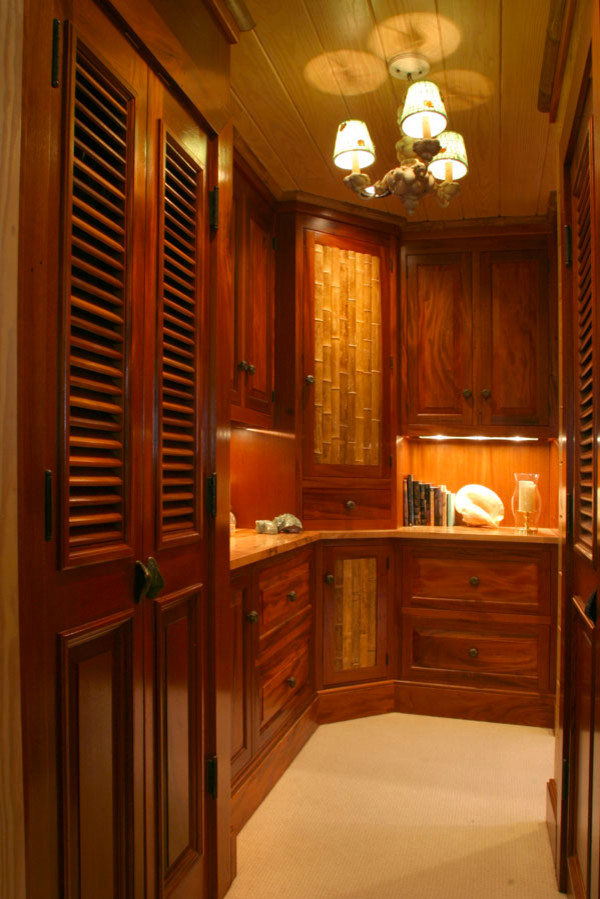 Photo of a medium sized world-inspired gender neutral walk-in wardrobe in Other with dark wood cabinets, raised-panel cabinets and carpet.