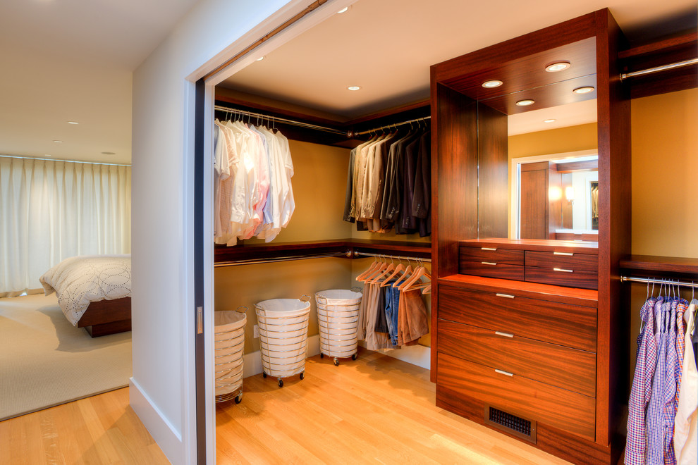 Cette photo montre un dressing room moderne en bois foncé de taille moyenne pour un homme avec un placard à porte plane, un sol en bois brun et un sol marron.