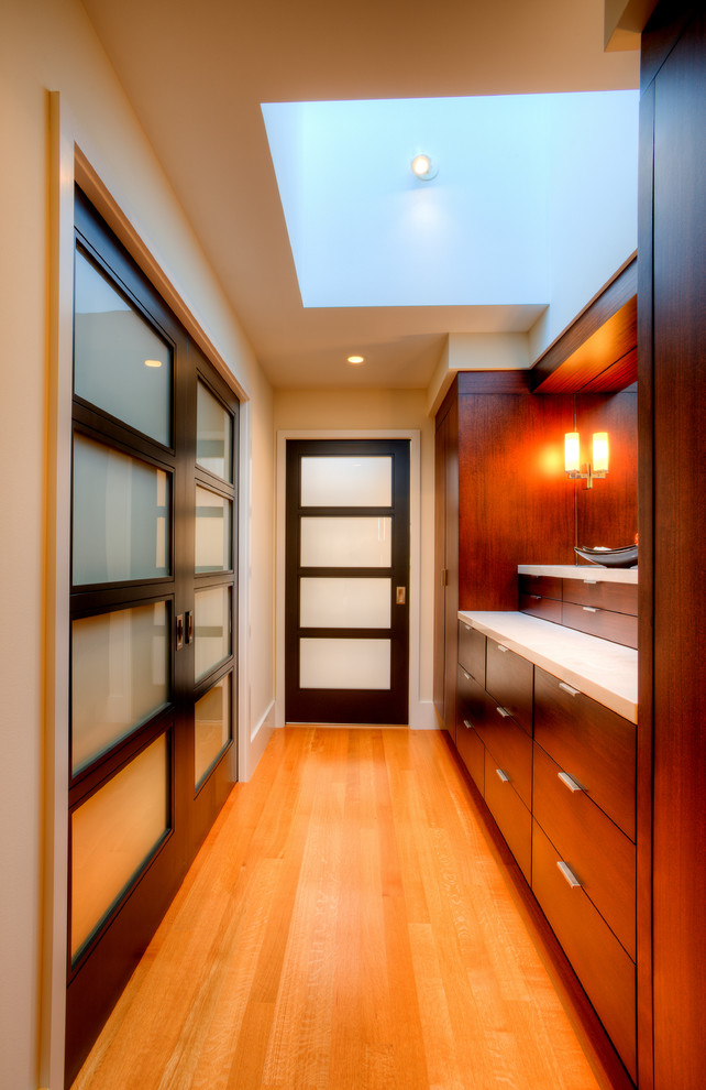 Imagen de vestidor de hombre minimalista de tamaño medio con armarios con paneles lisos, puertas de armario de madera en tonos medios, suelo de madera en tonos medios y suelo marrón