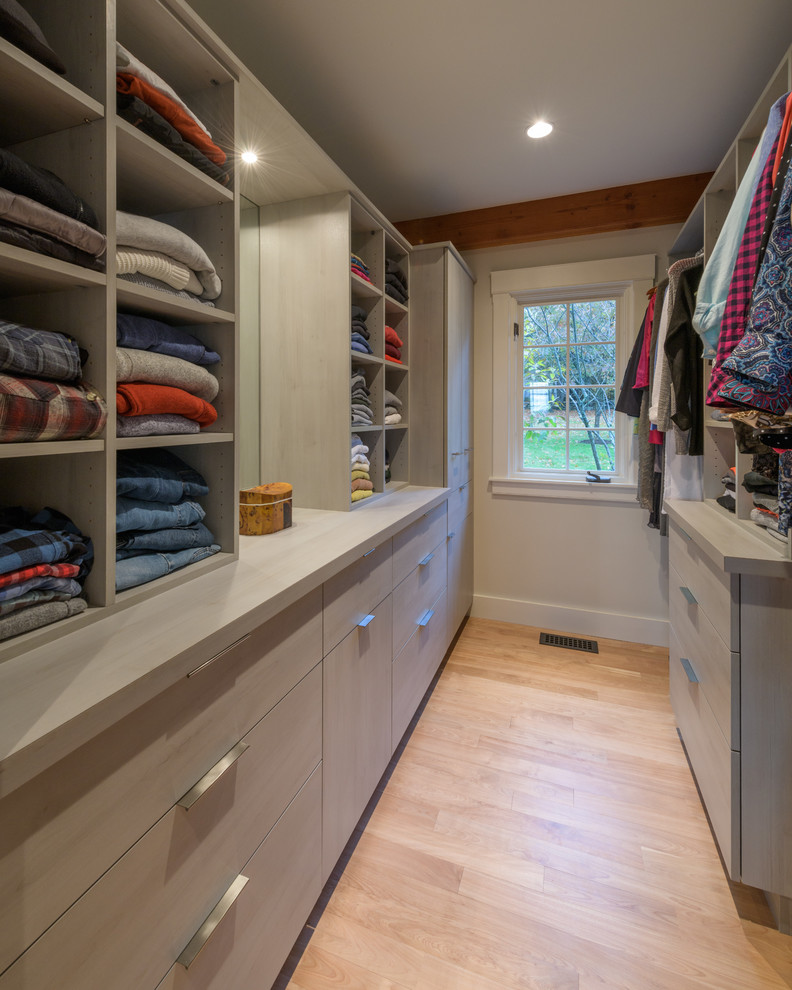Diseño de armario y vestidor unisex de tamaño medio con armarios con paneles lisos, puertas de armario grises y suelo de madera clara