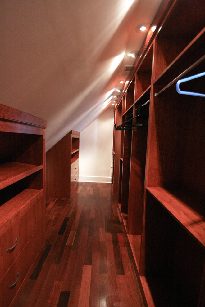 Example of a large classic gender-neutral medium tone wood floor walk-in closet design in DC Metro with medium tone wood cabinets
