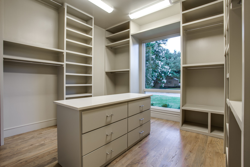 Idée de décoration pour un grand dressing minimaliste neutre avec un placard à porte plane, des portes de placard beiges et parquet clair.