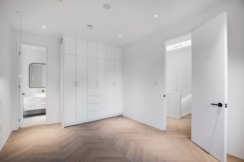 Mittelgroßes, Neutrales Klassisches Ankleidezimmer mit Einbauschrank, flächenbündigen Schrankfronten, weißen Schränken, hellem Holzboden und weißem Boden in Toronto