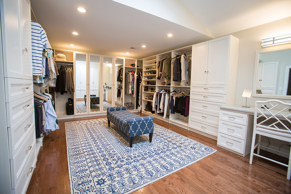 Ejemplo de armario vestidor unisex tradicional renovado grande con armarios con paneles empotrados, puertas de armario blancas y suelo de madera en tonos medios