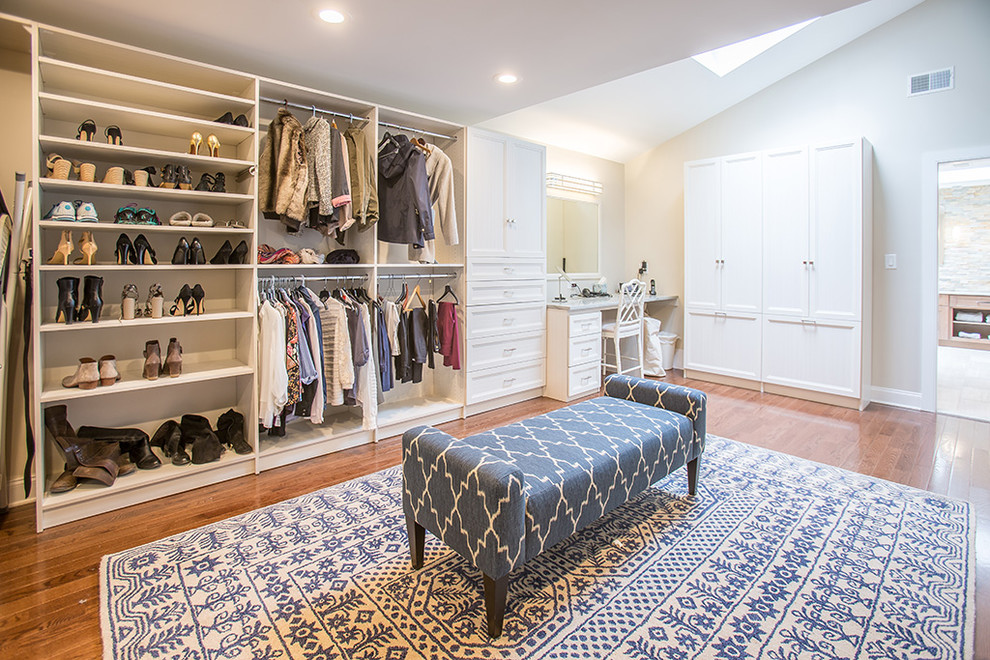 Foto de armario vestidor unisex clásico renovado grande con armarios con paneles empotrados, puertas de armario blancas y suelo de madera en tonos medios