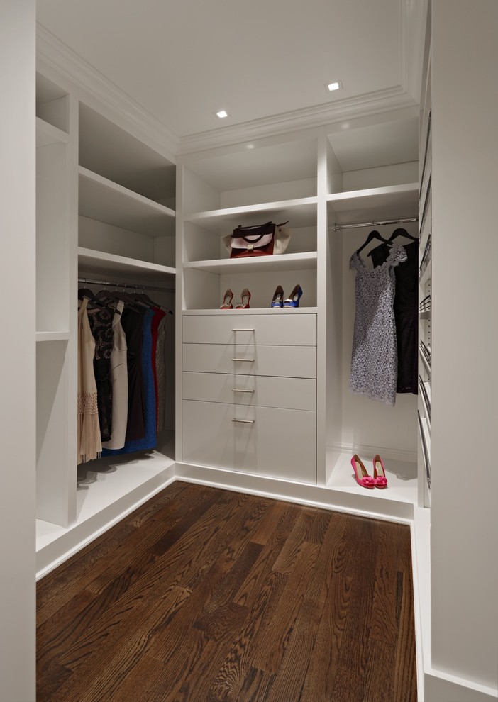 Aménagement d'un dressing room moderne pour une femme avec un placard à porte plane, des portes de placard blanches et parquet foncé.