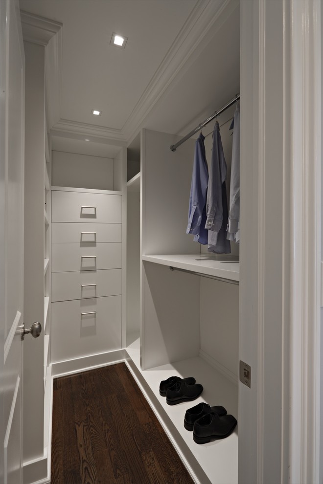 Idée de décoration pour un dressing room minimaliste pour un homme avec un placard à porte plane, des portes de placard blanches et parquet foncé.