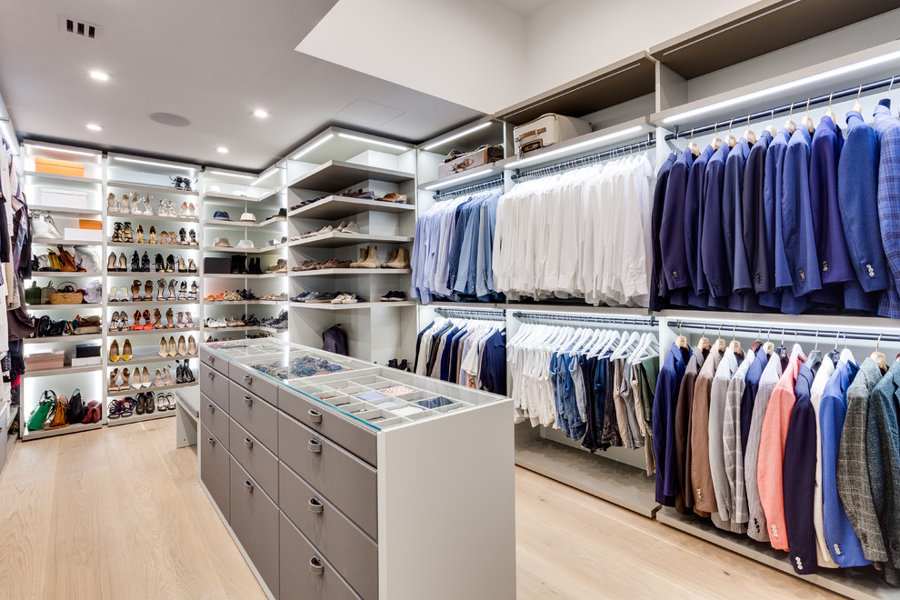Diseño de vestidor unisex actual con armarios abiertos, puertas de armario grises, suelo de madera clara y suelo beige