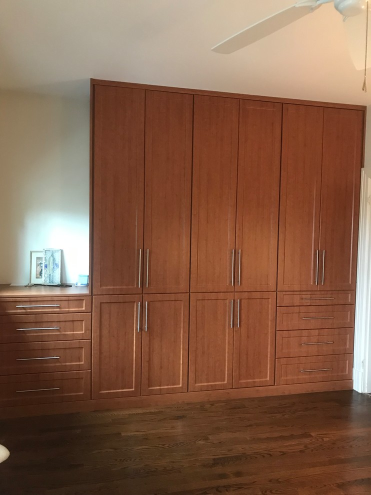 Ejemplo de armario moderno de tamaño medio con armarios con paneles empotrados, puertas de armario de madera oscura, suelo de bambú y suelo marrón