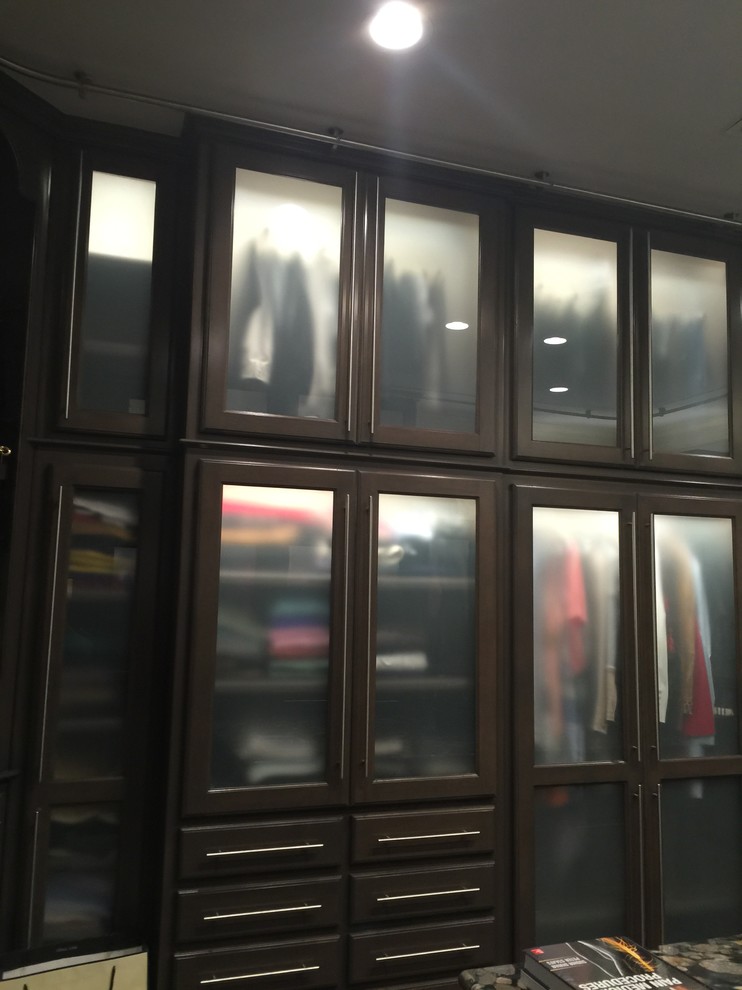 Imagen de armario vestidor unisex tradicional renovado grande con armarios tipo vitrina, puertas de armario de madera oscura y moqueta