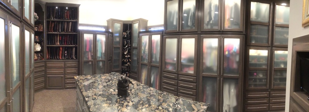 Ejemplo de armario vestidor unisex clásico renovado grande con armarios tipo vitrina, puertas de armario de madera oscura, moqueta y suelo marrón