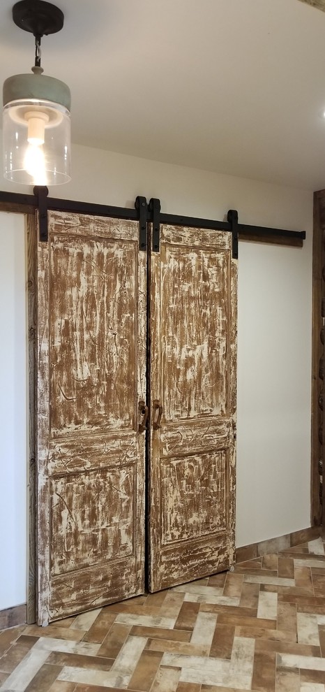 Réalisation d'un dressing room champêtre en bois vieilli de taille moyenne et neutre avec un placard avec porte à panneau surélevé, un sol en brique et un sol multicolore.