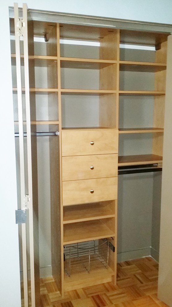 Diseño de armario unisex moderno pequeño con armarios con paneles lisos, suelo de madera en tonos medios y puertas de armario beige