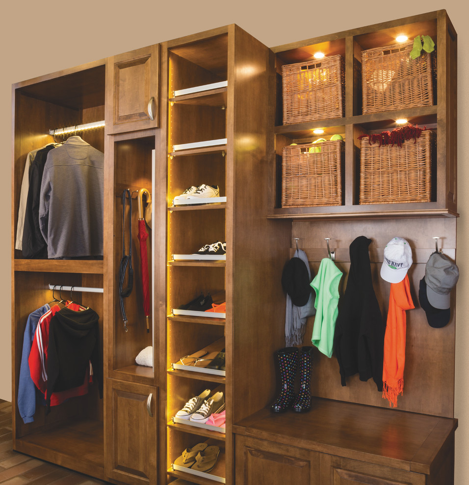 Ejemplo de armario unisex pequeño con armarios con paneles con relieve, puertas de armario de madera oscura, suelo de madera en tonos medios y suelo marrón