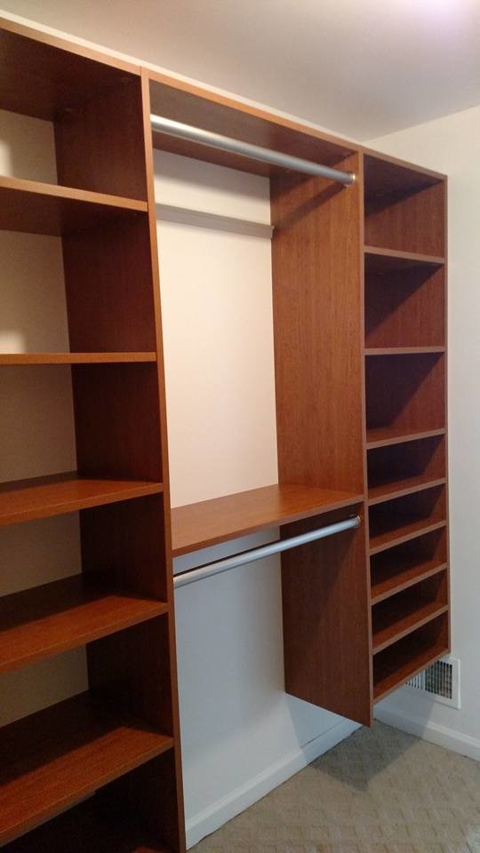 Reach-in closet - mid-sized modern gender-neutral carpeted reach-in closet idea in New York with flat-panel cabinets and medium tone wood cabinets