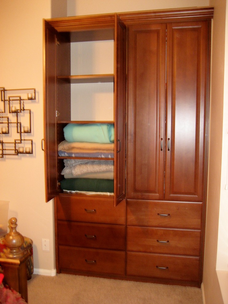 Foto de armario unisex tradicional pequeño con armarios con paneles con relieve y puertas de armario de madera oscura