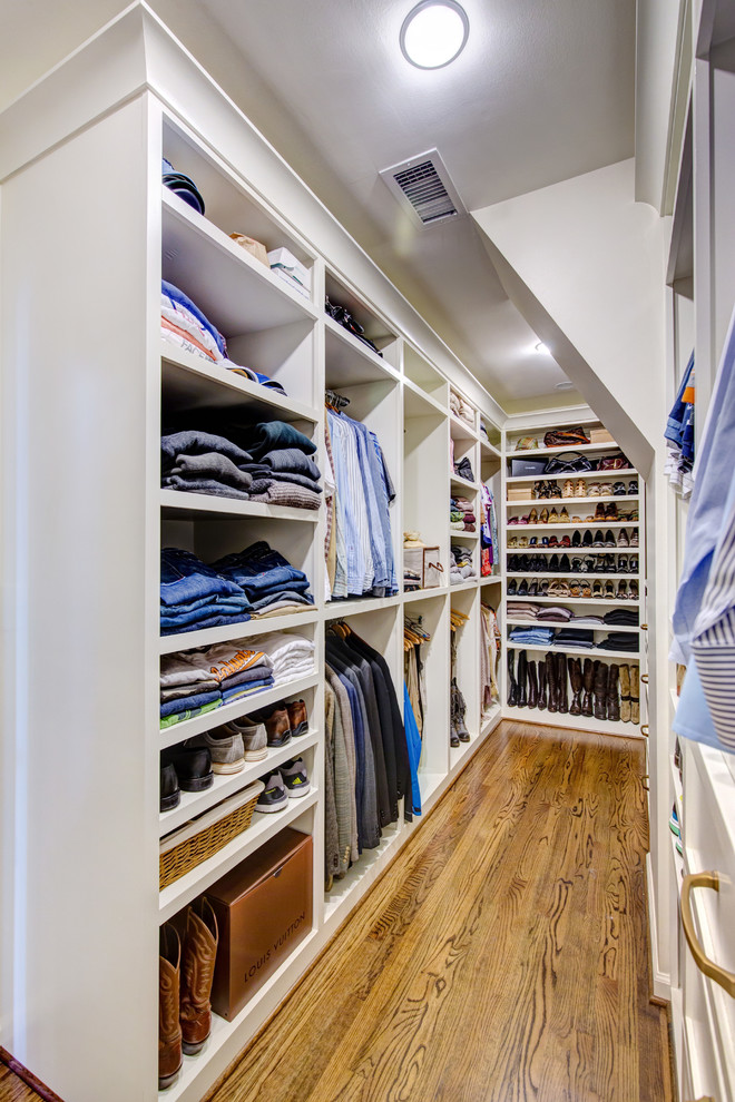 Imagen de armario vestidor unisex campestre de tamaño medio con armarios abiertos, puertas de armario blancas, suelo de madera en tonos medios y suelo marrón
