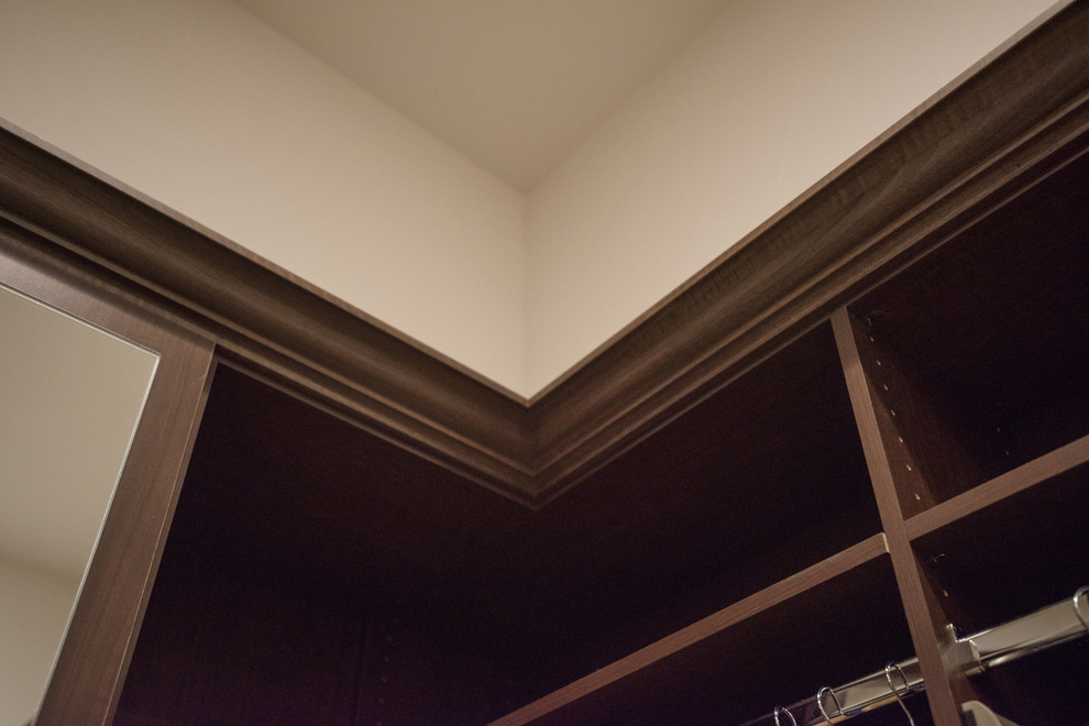 Foto de armario vestidor unisex clásico grande con armarios con paneles con relieve, puertas de armario de madera oscura, moqueta y suelo blanco