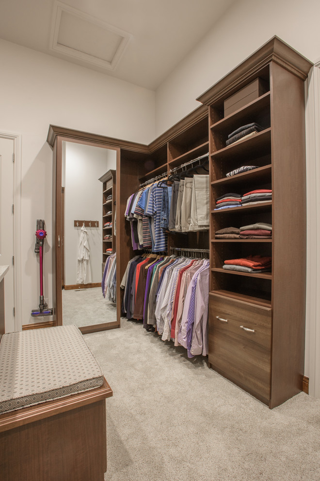 Imagen de armario vestidor unisex tradicional grande con armarios con paneles con relieve, puertas de armario de madera oscura, moqueta y suelo gris