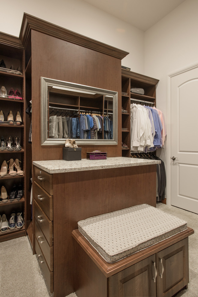Imagen de armario vestidor unisex clásico grande con armarios con paneles con relieve, puertas de armario de madera oscura, moqueta y suelo gris