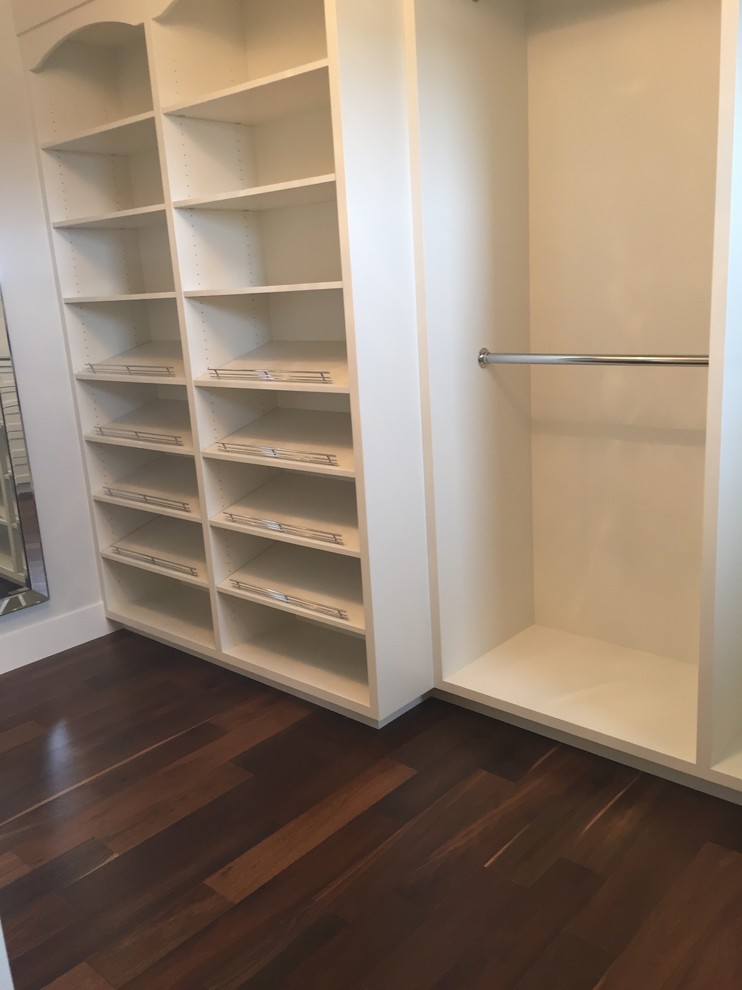 Design ideas for a large contemporary gender neutral walk-in wardrobe in Calgary with recessed-panel cabinets, white cabinets, medium hardwood flooring and brown floors.