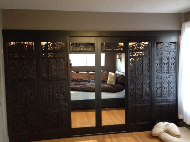 Design ideas for a world-inspired walk-in wardrobe in Montreal with glass-front cabinets and dark wood cabinets.