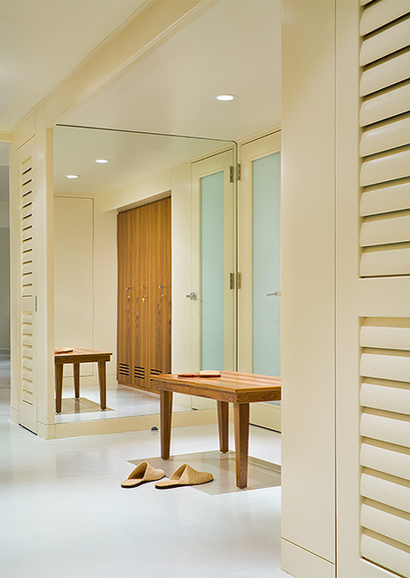 Cette image montre un grand dressing room design en bois brun neutre avec un placard à porte persienne, sol en béton ciré et un sol blanc.
