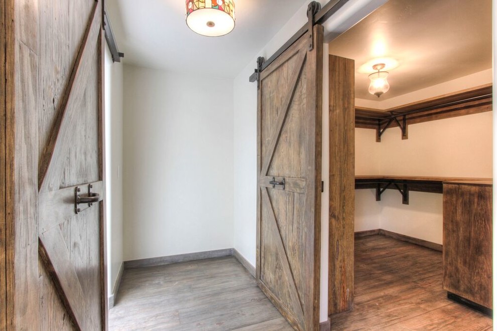 Ejemplo de armario vestidor unisex de estilo de casa de campo grande con armarios abiertos, puertas de armario de madera oscura y suelo de madera en tonos medios