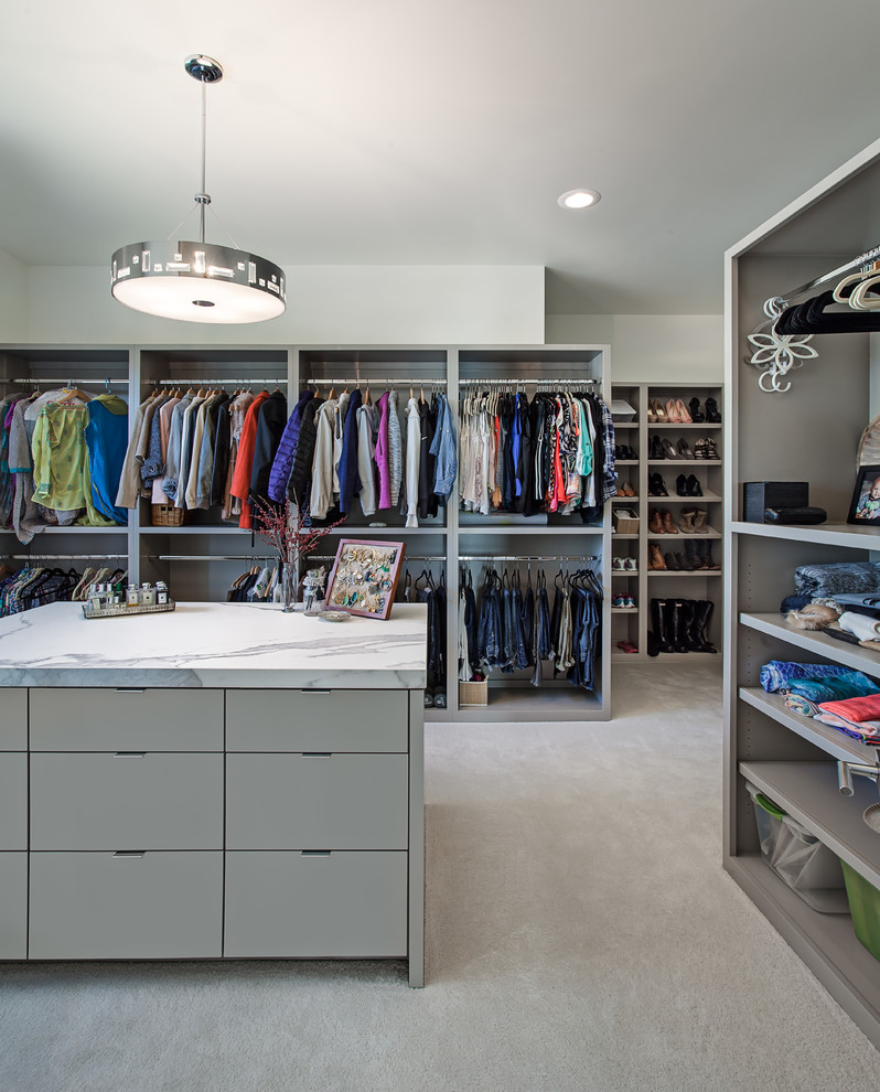This is an example of a large contemporary gender neutral walk-in wardrobe in Austin with flat-panel cabinets, grey cabinets, carpet and beige floors.