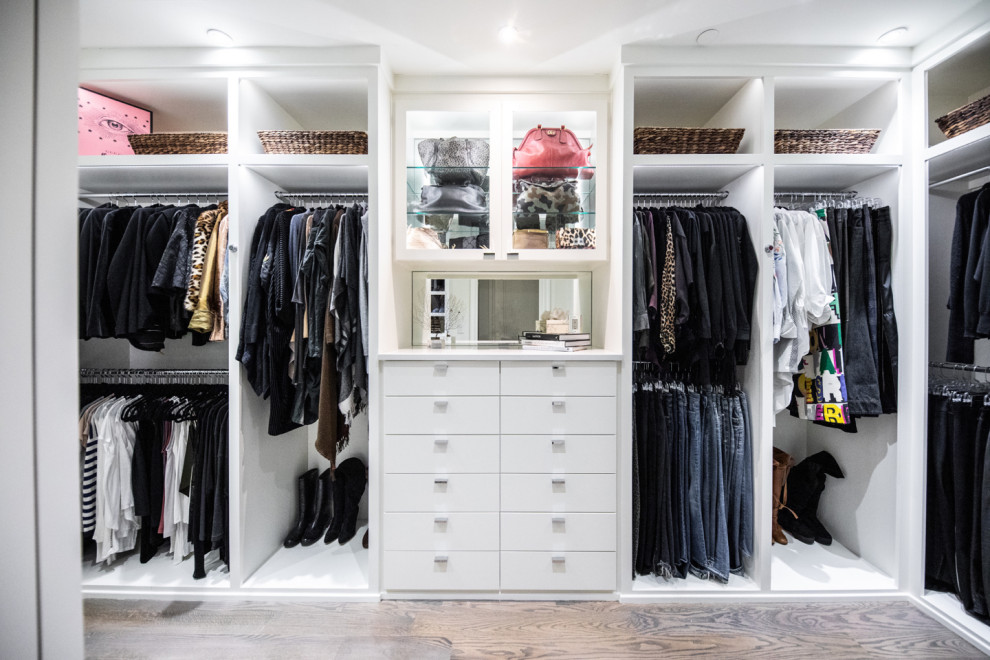 Ejemplo de armario vestidor unisex actual de tamaño medio con armarios con paneles lisos, puertas de armario blancas, suelo de madera en tonos medios y suelo marrón