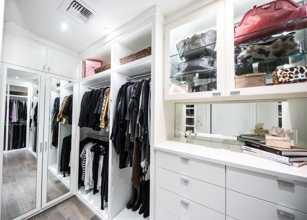 Example of a mid-sized trendy gender-neutral medium tone wood floor and brown floor walk-in closet design in Dallas with flat-panel cabinets and white cabinets