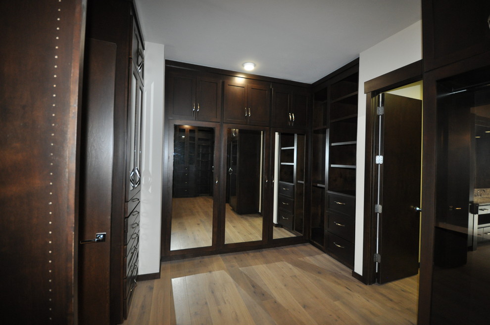 Geräumiges, Neutrales Modernes Ankleidezimmer mit Ankleidebereich, flächenbündigen Schrankfronten, dunklen Holzschränken und hellem Holzboden in Oklahoma City