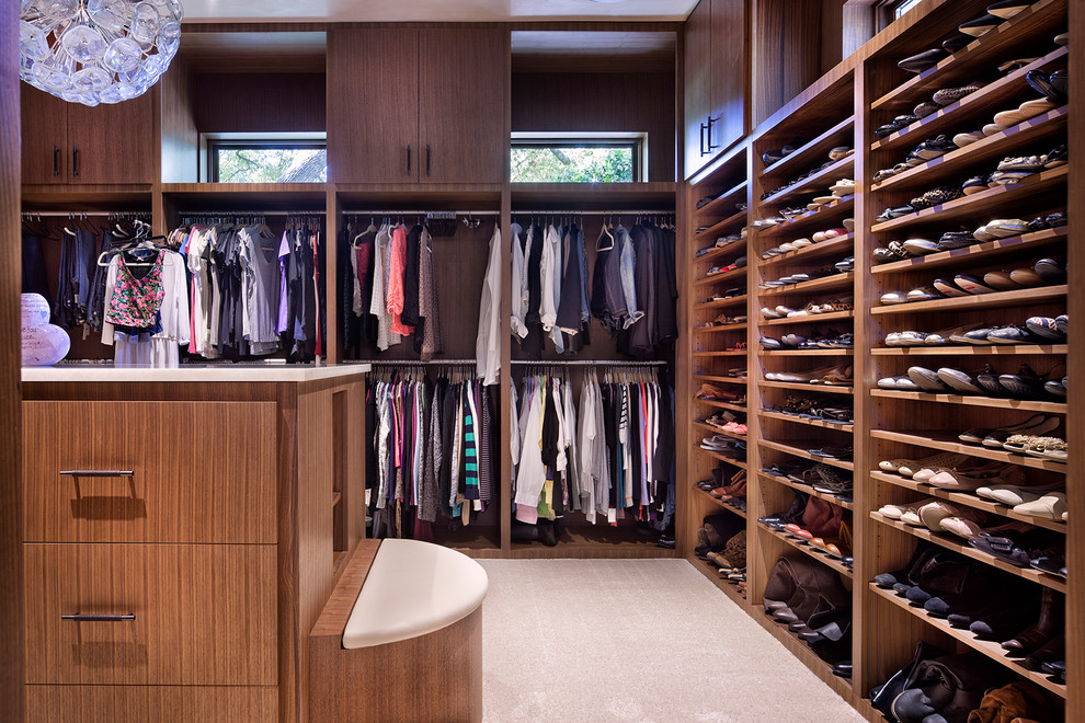 Photo of a contemporary gender neutral dressing room in Austin with flat-panel cabinets, medium wood cabinets, carpet and beige floors.