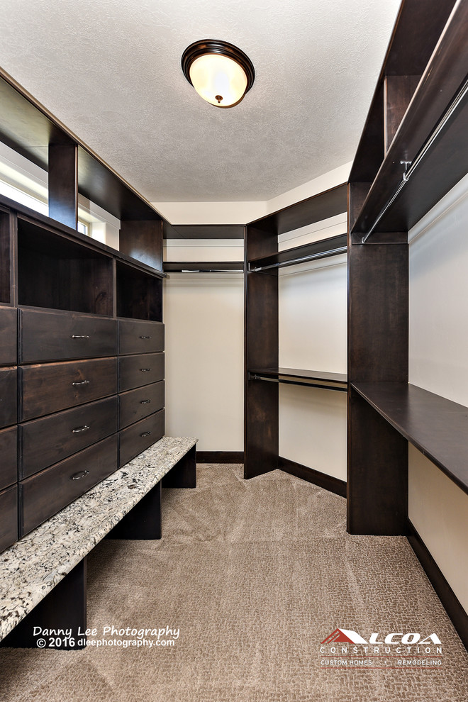 Design ideas for a large mediterranean dressing room in Salt Lake City with raised-panel cabinets, dark wood cabinets and carpet.